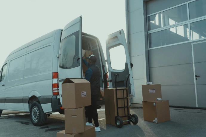 Worker unloading a Sprinter van at a warehouse in the morning, illustrating efficient delivery and logistics operations.